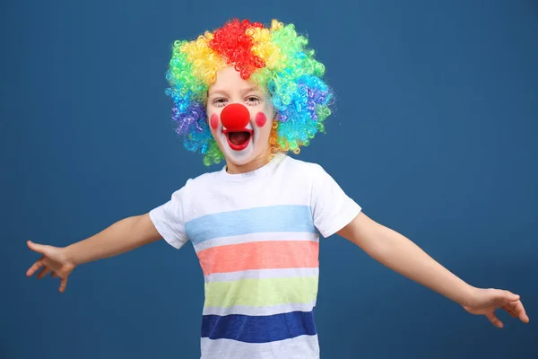 Cute little boy with clown makeup in rainbow wig on color background. April fool's day celebration — Stock Photo, Image