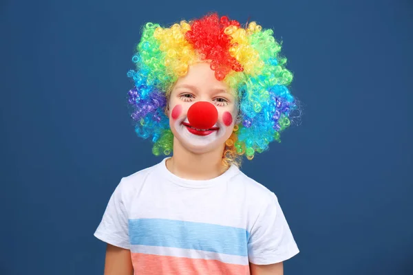 Ragazzino carino con trucco clown in parrucca arcobaleno su sfondo colore. Festa dello sciocco di aprile — Foto Stock