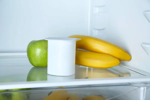 Plastikbecher mit Joghurt, Bananen und Apfel im Kühlschrank — Stockfoto