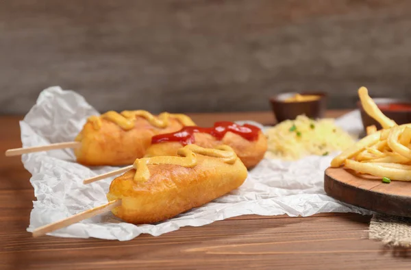 Tasty corn dogs with sauces on table — Stock Photo, Image