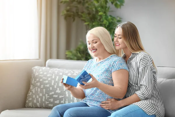 Joven hija dando caja de regalo a la madre en casa — Foto de Stock