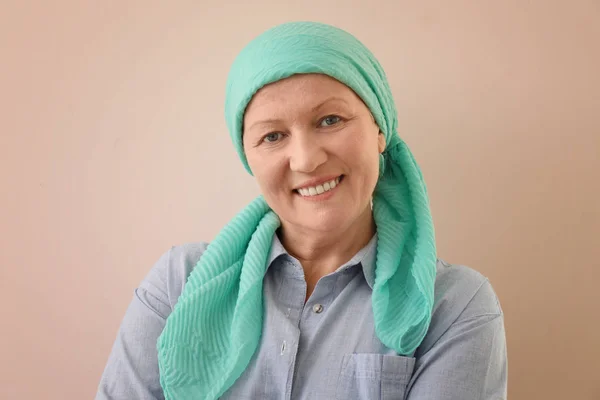 Reife Frau mit Krebs im Kopftuch auf farbigem Hintergrund — Stockfoto