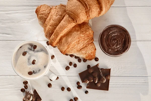 Gustosi croissant con tazza di caffè e salsa di cioccolato sul tavolo di legno — Foto Stock