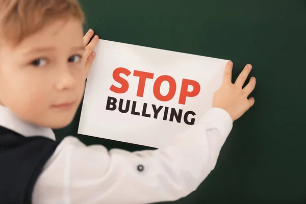 Μικρό αγόρι να κολλήσει πινακίδα με λέξεις «Stop εκφοβισμού» Μαυροπίνακας — Φωτογραφία Αρχείου
