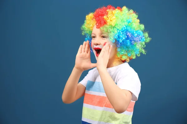 Cute little boy with clown makeup in rainbow wig on color background. April fool's day celebration — Stock Photo, Image