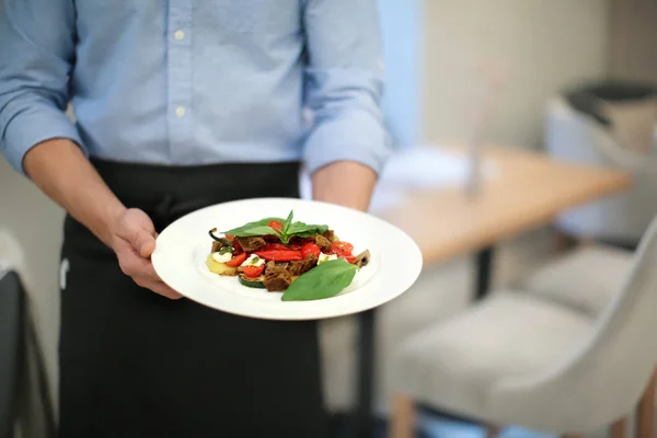 Kellner hält Teller mit Gemüsesalat drinnen, Nahaufnahme — Stockfoto