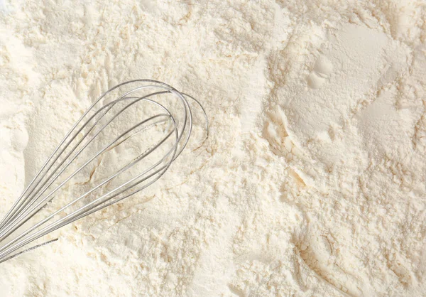 Metal whisk on white wheat flour — Stock Photo, Image