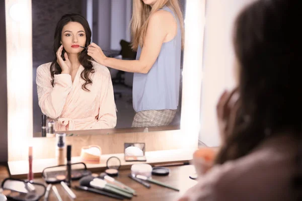 Reflexão no espelho do artista de maquiagem preparando noiva antes de seu casamento dentro de casa — Fotografia de Stock