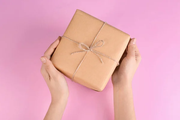 Woman holding parcel on color background — Stock Photo, Image