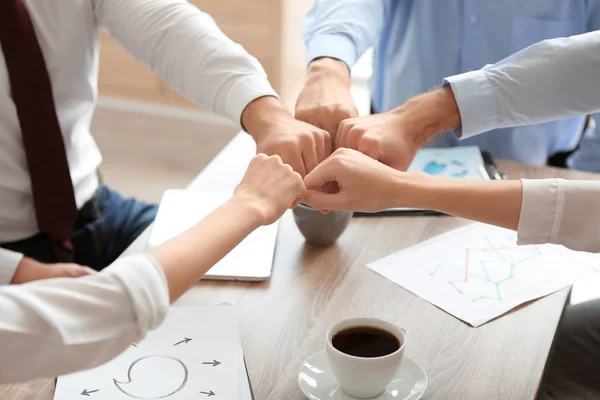 people in office wear putting hands together