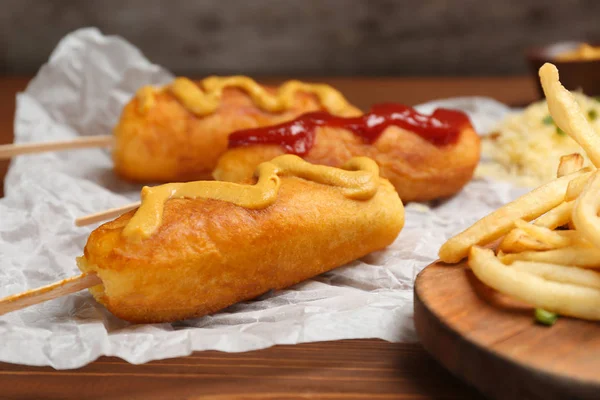 Sabrosos perritos de maíz con salsas en la mesa, primer plano — Foto de Stock