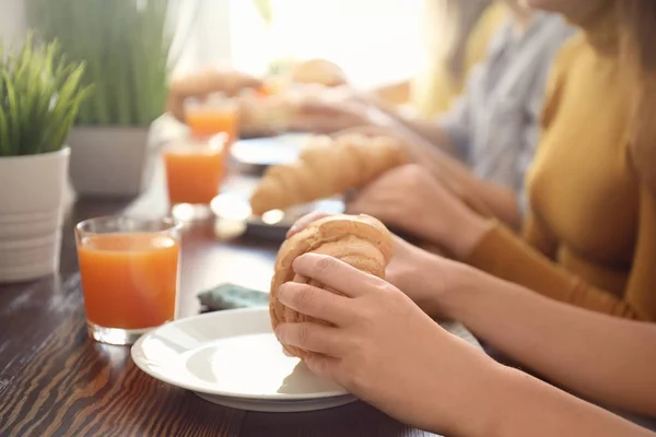 Women eating fresh croissants at table in cafe — Stock Photo, Image