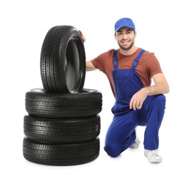 Beyaz arka plan üzerinde araba lastikleri ile üniformalı genç makinist