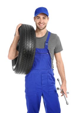 Beyaz arka plan üzerinde otomobil lastiği ile üniformalı genç makinist