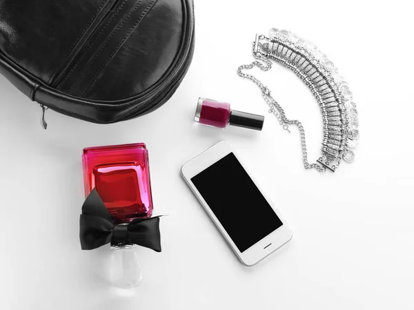 Bouteille de parfum, smartphone et collier sur fond blanc — Photo