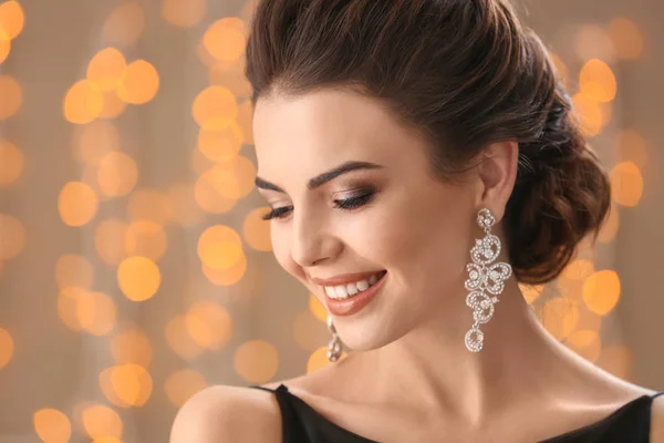 Mulher bonita com jóias elegantes contra luzes desfocadas — Fotografia de Stock