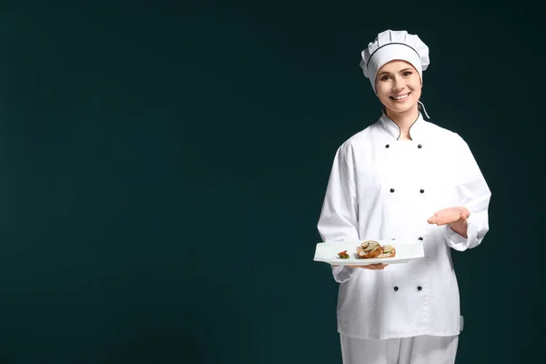 Chef feminino em uniforme com prato saboroso em fundo escuro — Fotografia de Stock