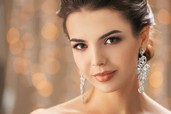 Hermosa mujer joven con joyas elegantes contra luces desenfocadas — Foto de Stock