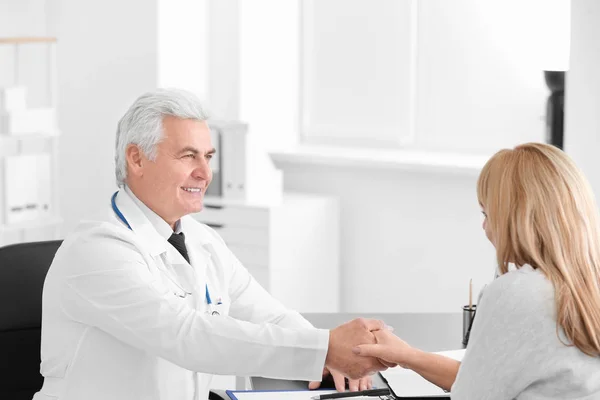 Médico masculino e paciente apertando as mãos durante consulta na clínica — Fotografia de Stock