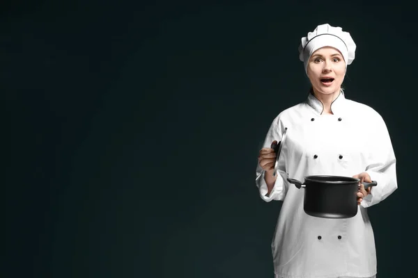 Femme chef en uniforme avec casserole sur fond sombre — Photo