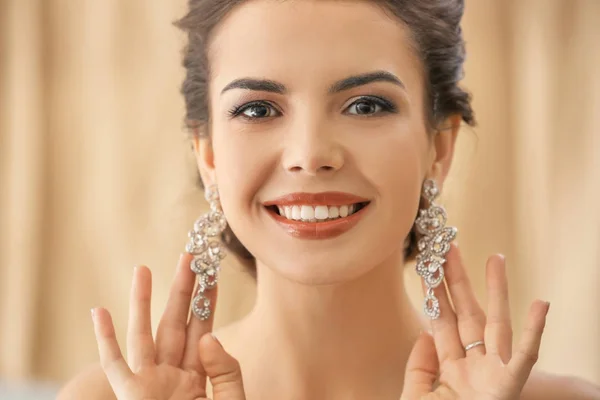 Beautiful young woman with elegant jewelry on color background — Stock Photo, Image