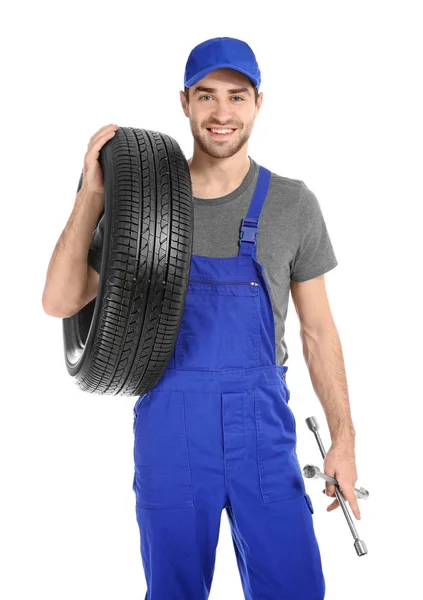 Jovem mecânico em uniforme com pneu de carro no fundo branco — Fotografia de Stock