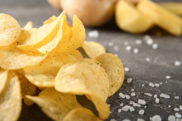Mumsig krispig potatis chips med salt på grå bord — Stockfoto