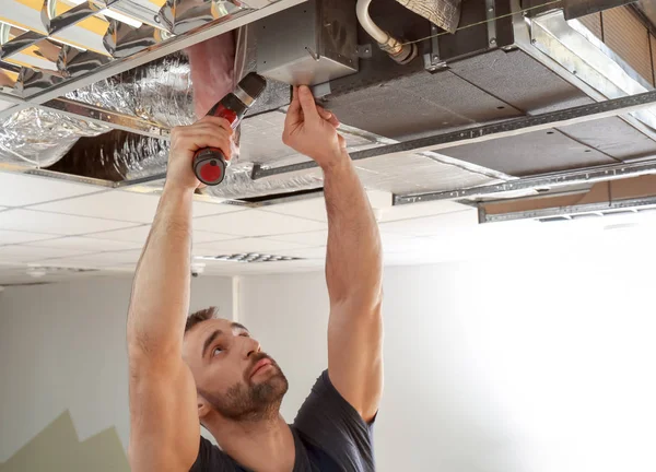 Männlicher Techniker repariert industrielle Klimaanlage in Innenräumen — Stockfoto