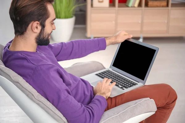 Pria dengan laptop duduk di kursi yang nyaman di rumah — Stok Foto