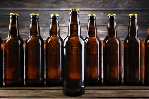 Birra fresca in bottiglie di vetro su sfondo di legno — Foto Stock