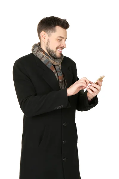 Mladý muž s mobilním telefonem na bílém pozadí. Připraveni na zimní dovolenou — Stock fotografie