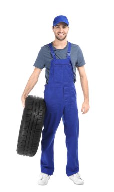 Beyaz arka plan üzerinde otomobil lastiği ile üniformalı genç makinist