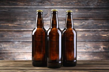 Ahşap arka planda cam şişelerde taze bira.