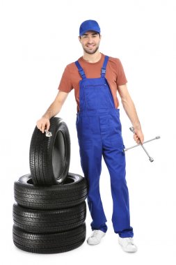 Beyaz arka plan üzerinde araba lastikleri ile üniformalı genç makinist
