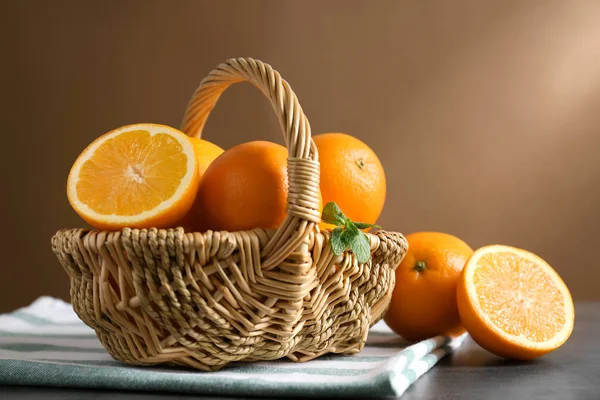 Cesta de mimbre con jugosas naranjas maduras en la mesa — Foto de Stock