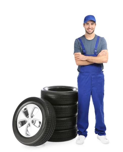 Young mechanic in uniform with car tires on white background — Stock Photo, Image