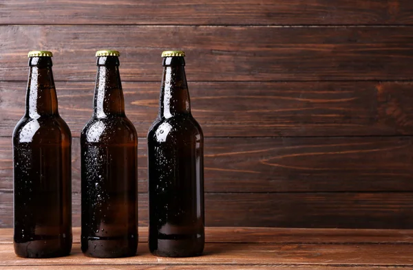 Cerveza fresca en botellas de vidrio sobre fondo de madera —  Fotos de Stock