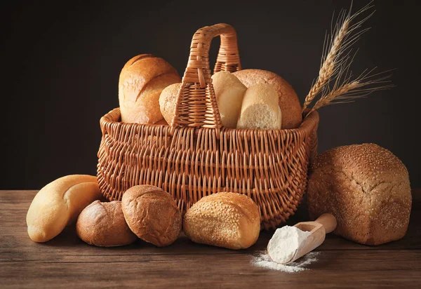 Композиція зі свіжим смачним хлібом на дерев'яному столі на темному фоні — стокове фото