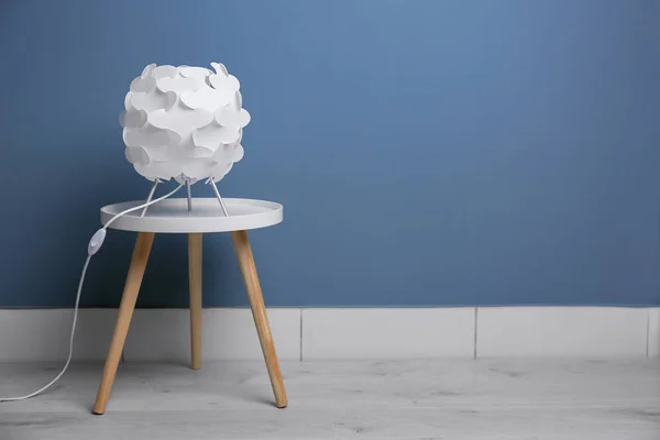 Elegante lámpara en la mesa cerca de la pared de color — Foto de Stock