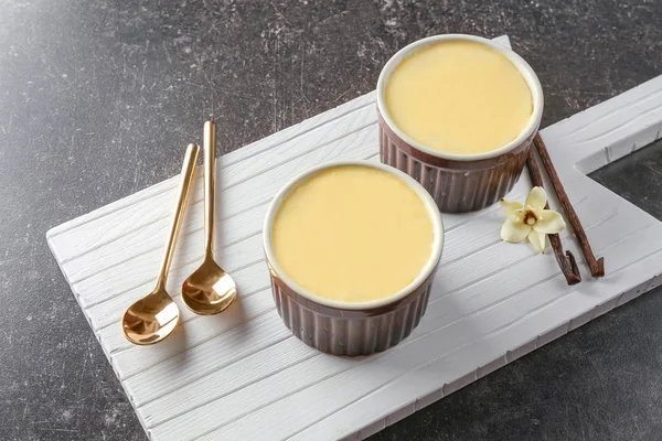 Ramekins con gustoso budino alla vaniglia su tavola di legno — Foto Stock
