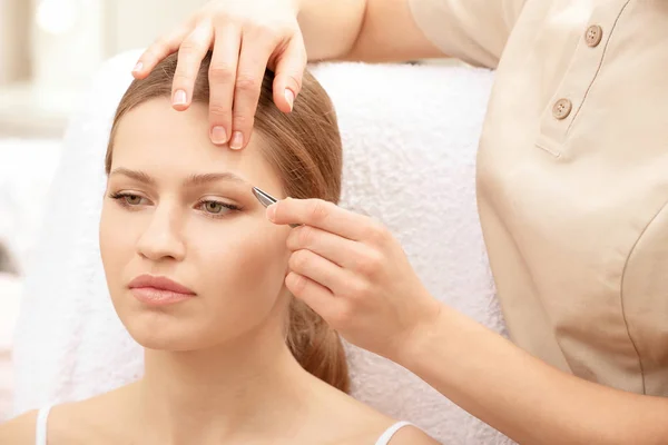Ung kvinna som genomgår ögonbryn korrigeringsförfarandet i salong — Stockfoto