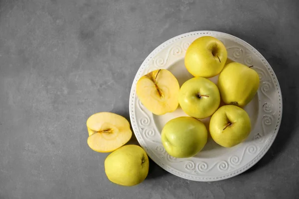 Placa con manzanas amarillas maduras sobre fondo gris — Foto de Stock