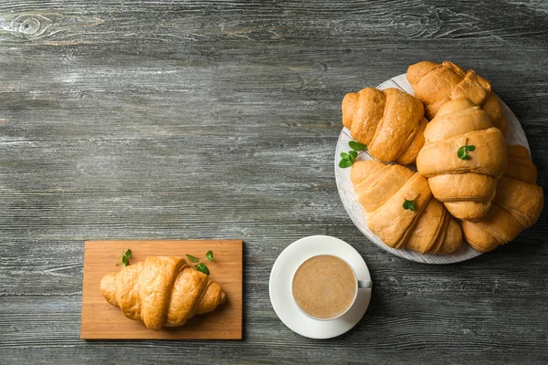 Croissants deliciosos com xícara de café na mesa de madeira — Fotografia de Stock