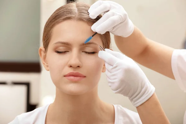 Young woman undergoing eyebrow correction procedure in salon — Stock Photo, Image