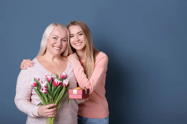 花と色の背景上のギフト ボックスの母持株花束と若い娘 — ストック写真