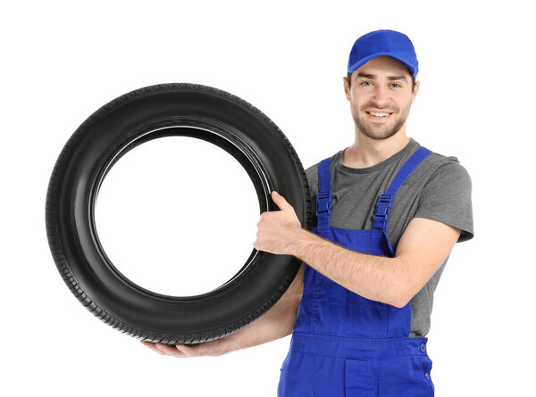 Young mechanic in uniform with car tire on white background