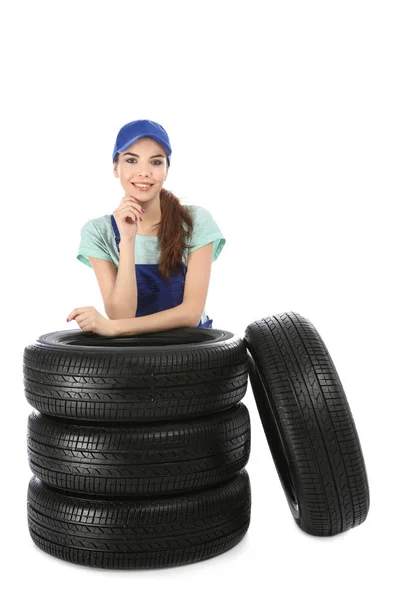 Giovane meccanico in uniforme con pneumatici auto su sfondo bianco — Foto Stock