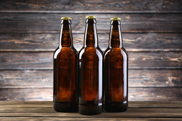 Ahşap arka planda cam şişelerde taze bira.