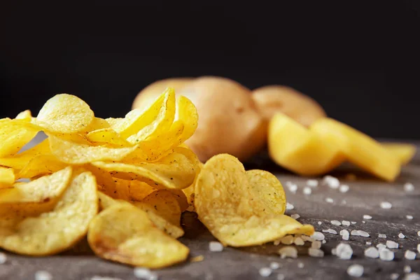 Deliciosas papas fritas crujientes con sal en la mesa gris sobre fondo oscuro — Foto de Stock