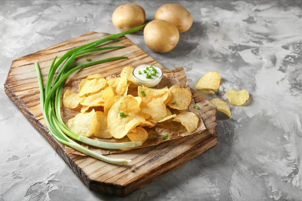 Krispig potatis chips med grön lök och gräddfil på träskiva — Stockfoto